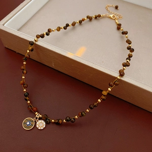 Detail of tiger eye bead necklace with evil eye and star pendants on a jewelry tray