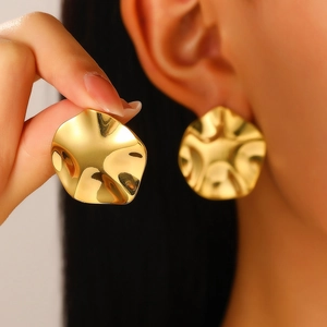 Macro detail of irregular pleated 18K gold plated earrings with a glossy hammered finish