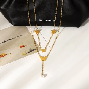 Detailed macro view of 18K gold double layer necklace with butterfly charms and pearl pendant