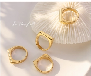 Detailed view of four gold-plated minimalist square-top geometric rings on a white surface