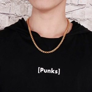 Gros plan d'une chaîne collier dorée pour homme portée sur un sweat à capuche noir