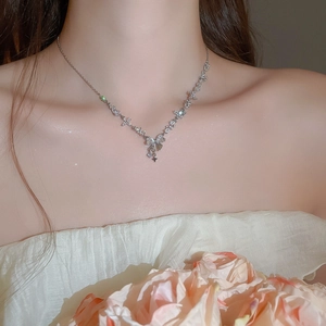 Close-up of sparkling bow and star pendant necklace on model with elegant jewelry details