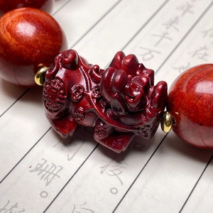 Macro di una perla PiXiu in legno di sandalo rosso intagliato con distanziatori dorati