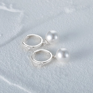 Macro detail of elegant pearl earrings with silver base and sparkling cubic zirconia