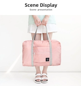 Close-up of pink foldable travel bag with front zipper pocket and durable grey handles