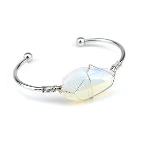 Macro shot of silver wire-wrapped white crystal stone on minimalist open cuff bracelet
