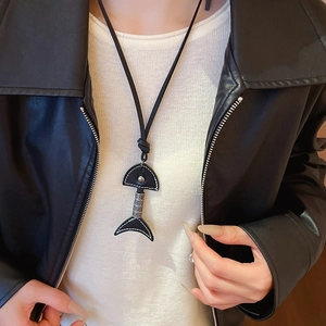 Close-up of black leather fishbone pendant necklace with white stitching and metal details