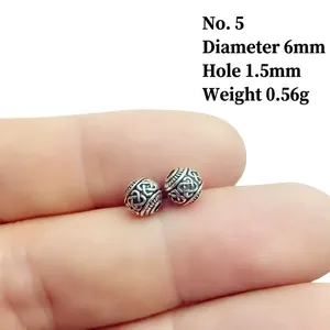 Macro detail of 6mm vintage silver alloy beads showing intricate embossed knot textures