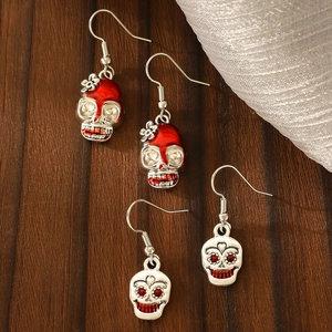 Gothic skull earrings with red enamel and rhinestones on dark wood background