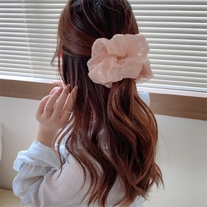 Detail view of a large pink iridescent scrunchie styled on a woman's ponytail ponytail