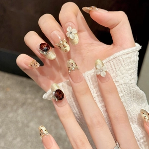 Detailed view of handmade luxury press-on nails with 3D flowers and amber gemstones.