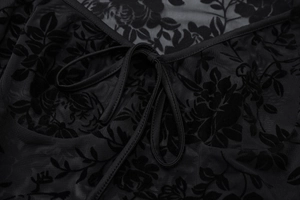 Détail du haut en maille noire avec texture florale floquée et lien au col
