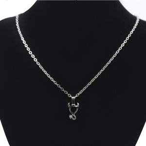 Detail of silver heart pendant with black zircon, devil horns and tail on black mannequin