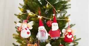Close-up of assorted plush Christmas ornaments hanging on a tree with warm fairy lights