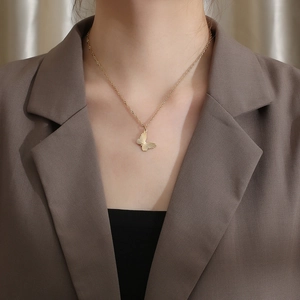 Macro detail of elegant golden butterfly pendant necklace with textured pattern on a model