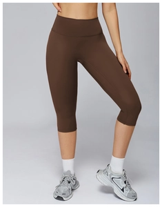 Macro detail of seamless brown high-waisted yoga capri pants with matte fabric texture