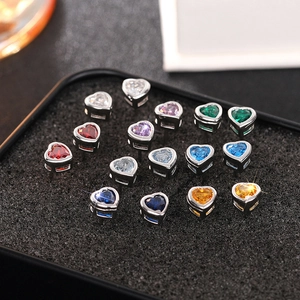 Macro view of colorful heart-shaped gemstone stud earrings set in silver claw settings