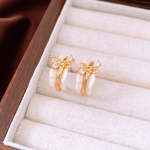 Detailed close-up of 18k gold plated bow earrings with crystals on a jewelry tray
