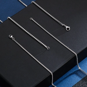 Detailed view of polished stainless steel box chains on a professional black stand