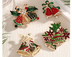 Detailed view of four festive Christmas bell brooches with red enamel and crystals