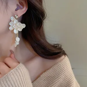 Détail de boucles d'oreilles fleurs avec pétales blancs et perles sur un mannequin