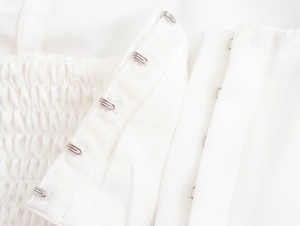 Detailed macro view of back metal button row on white fabric backless top