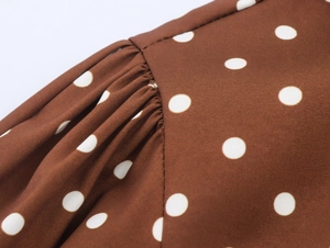 Makro-Detail der Nähte und gerafften Ärmel auf braunem Polka-Dot-Kleidstoff