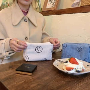 Detail of vintage corduroy makeup bags with embroidered smileys on a cafe table