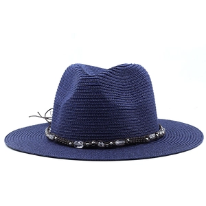 Detail of navy blue straw fedora hat featuring a beaded woven decorative band and wide brim