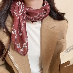 Detail of burgundy paisley silk scarf necklace paired with a camel blazer and white top