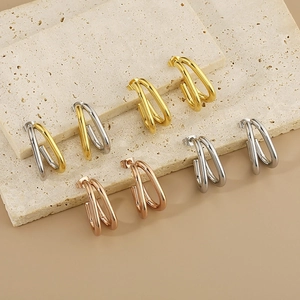 Créoles minimalistes en forme de U à double ligne en or, argent et or rose sur socle en pierre