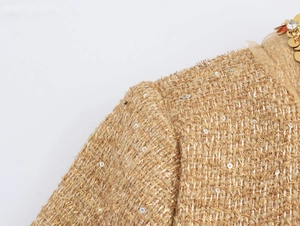 Detail of tweed fabric jacket featuring gold sequins, metallic threads and rhinestones