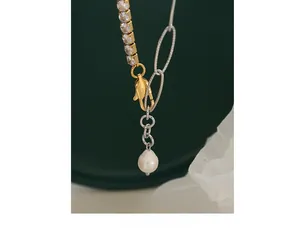 Detail showing mixed metal chain necklace with zircon stones and pearl pendant