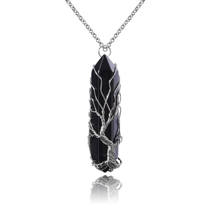 Macro view of handmade wire wrapped tree of life pendant on black crystal pillar