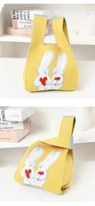 Detail of yellow knitted handbag with cute rabbit and red heart pattern on white shelf