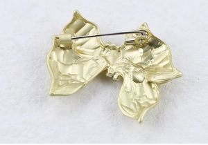 Detailed back view of the bow brooch showing the safety pin clasp and hammered texture