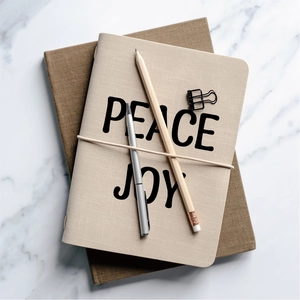 Detail view of PEACE and JOY journals on marble background with stationery set
