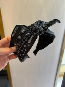 Détail d'un serre-tête noir à motif paisley avec nœud supérieur et tissu doux rétro