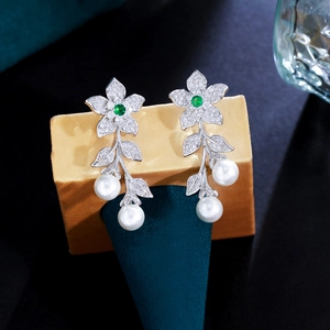 Macro detail of luxury floral pearl drop earrings with green zircon and silver tassels