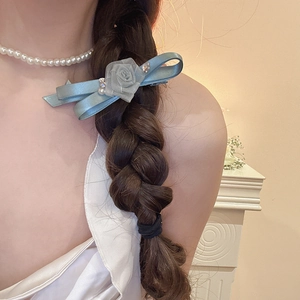Detail of light blue satin ribbon hair clip with mesh flower and pearl on side-braided hair