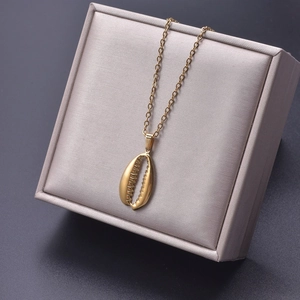 Close-up of golden shell pendant necklace displayed in a beige square jewelry box