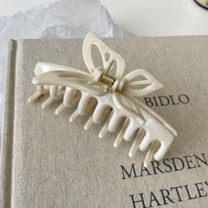 Close-up of a cream butterfly hair claw clip with marble texture on a linen book cover