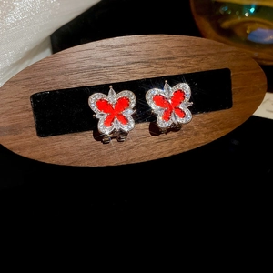 Macro shot of red butterfly stud earrings with sparkling crystal-set borders and accents