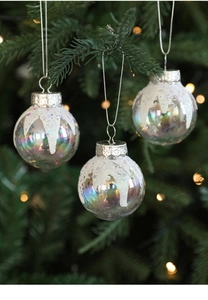 Close-up of iridescent Christmas balls with white glitter snow and silver caps on tree