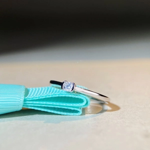 Macro shot of S925 sterling silver ring with square D color Moissanite on blue silk ribbon