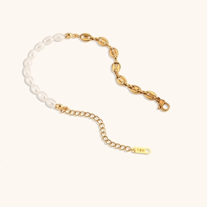 Close-up of asymmetric pearl and 18K gold-plated pig nose chain bracelet detail