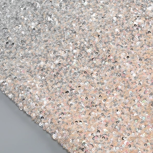 Close-up of sparkling champagne gold sequins on mesh fabric for elegant evening dresses