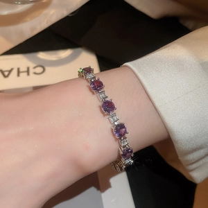 Detail of elegant silver bracelet featuring purple round and rectangular white crystals