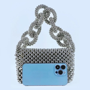 Silver beaded handbag detail showing handcrafted beads with ring handle and phone for scale