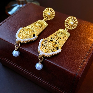 Detailed close-up of vintage golden hollow floral earrings with elegant white pearls
